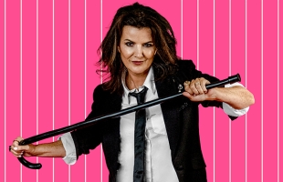 Deirdre O'Kane dressed in a tuxedo, with sleeves rolled up, holding a cane