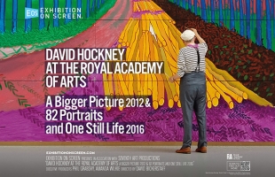 Person standing in front of a large, colorful David Hockney exhibition display at the Royal Academy of Arts, featuring bold text and a vibrant landscape artwork