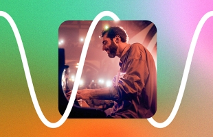 Portrait of Evgeny Grinko, a with dark hair and beard, playing piano under warm stage lighting, set against a vibrant gradient background with a white waveform graphic.