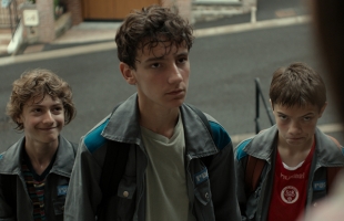 A still from The Fantastic Three depicting three scruffy-looking boys in their early teens, dressed in identical wide-collar jackets, looking up with cheeky expressions.