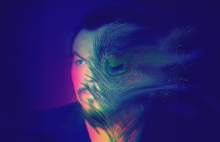 A creatively colourful photograph of the musical artist Jack Lukeman, his face appears multi coloured and one side dissolving into a peacock feather.