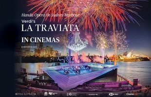 Promotional poster for Handa Opera on Sydney Harbour's production of Verdi’s La Traviata in Cinemas. The image features a outdoor stage built over Sydney Harbour at night, with performers dancing on an inclined, framed platform. Above the stage hangs a massive glowing chandelier beneath red and gold fireworks filling the sky. In the background, illuminated city skyscrapers, the Sydney Opera House, and the Harbour Bridge are visible across the water.