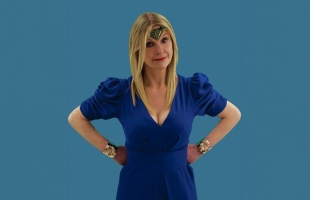 Sinéad Culbert stands with her hands on her hips, wearing a blue dress, a Wonder Woman tiara and bracelets