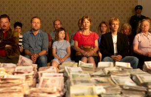 A selection of people, dressed in 80s/90s outfits, sit with a table covered in cash, wrapped in elastic bands