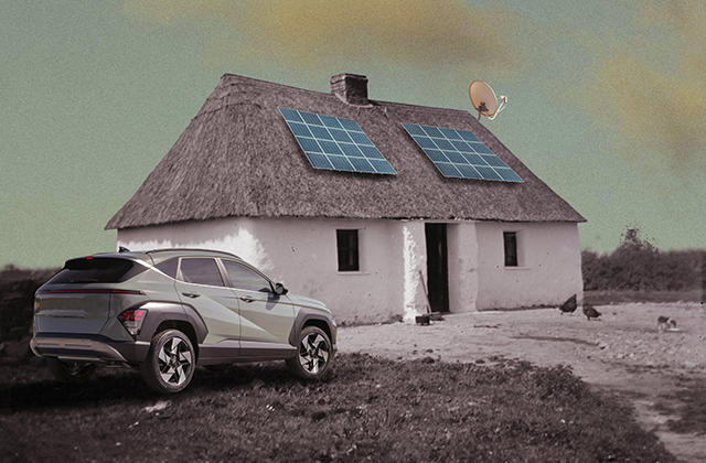 A composite image blending traditional and modern elements. In the foreground on the left, a sleek modern greyish-green SUV is parked on a dirt path. In the background stands a vintage, whitewashed cottage with a thatched roof. Two modern blue solar panels are mounted on the thatched roof, alongside a small satellite dish attached near the chimney. A few chickens roam the yard under a muted, overcast sky.