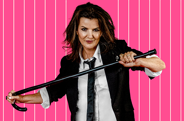 Deirdre O'Kane dressed in a tuxedo, with sleeves rolled up, holding a cane