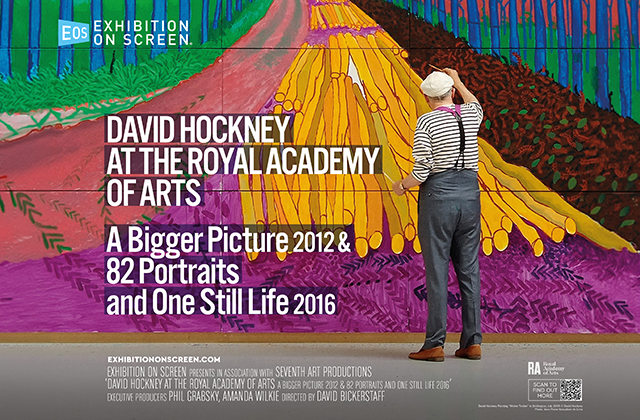 Person standing in front of a large, colorful David Hockney exhibition display at the Royal Academy of Arts, featuring bold text and a vibrant landscape artwork