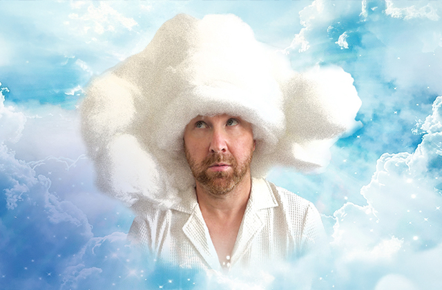 Jason Byrne, with a thoughtful expression, is shown against a dreamy sky filled with fluffy clouds. He wears a white shirt and has an oversized, cloud-like hat on his head, blending into the cloudy background.