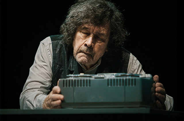 Stephen Rea, as Krapp, lovingly holding an old tape machine.