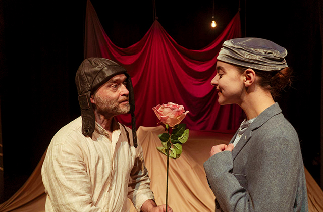 A man presenting a young woman with a pink rose.