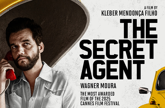 A film poster featuring a bearded man holding a red telephone receiver, looking serious and slightly upward. He stands inside what appears to be a curved, metallic structure. On the right side, bold black text reads “THE SECRET AGENT,” with smaller text above: “A film by Kleber Mendonça Filho,” and below: “Wagner Moura” and “The most awarded film of the 2025 Cannes Film Festival.” A partial yellow car is visible on the far right against a light, textured background.