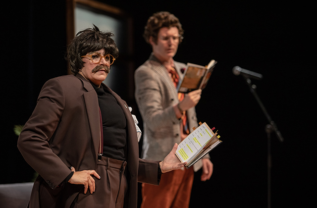 MASTERCLASS poster, Adrienne Truscott, dressed as a man, with a moustache, wearing over-sized jacket, holding a book and next to her Deidlim Cannon reading a book and a mic in front of them