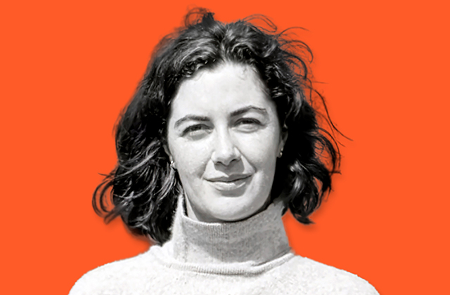 Irish writer Nuala O’Faoláin is pictured, the image is black and white, she looks toward the camera against a bright orange matte background. She is wearing a polo neck and holds a smile.