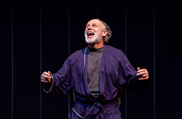 Don Wycherley in a blue robe, smiling widely.