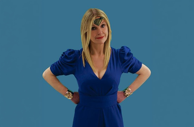 Sinéad Culbert stands with her hands on her hips, wearing a blue dress, a Wonder Woman tiara and bracelets