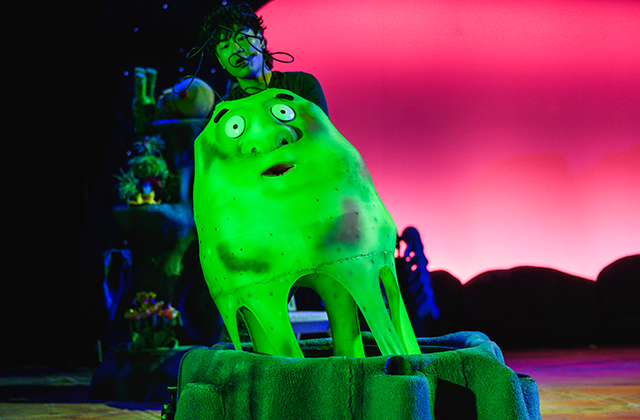A green glow-in-dark alien coming out of a crater